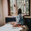woman sitting on bed looking outside the window